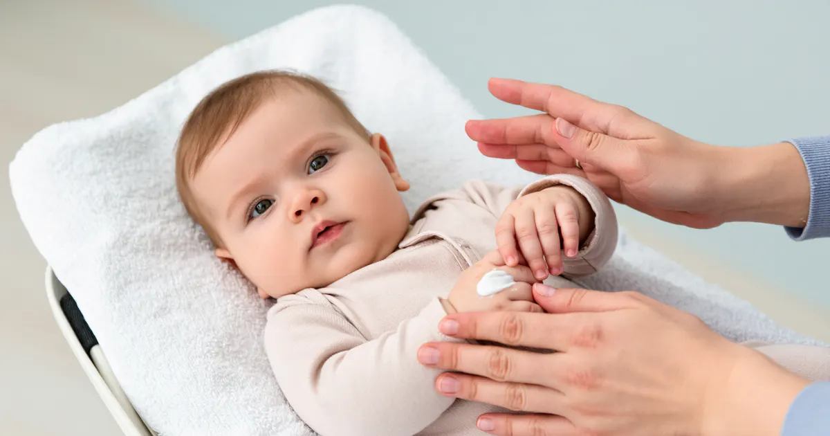 Cha mẹ thoa kem dưỡng ẩm dịu nhẹ cho vùng da khô của em bé