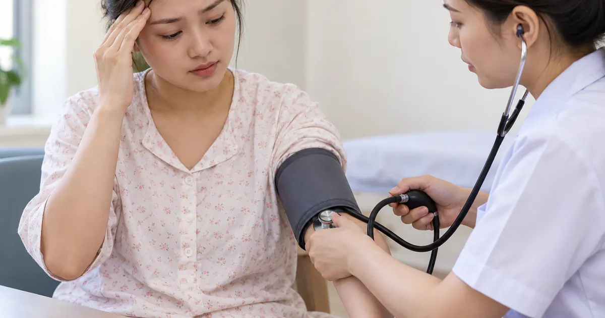 Nhân viên y tế kiểm tra huyết áp cho mẹ sau sinh có đau đầu chóng mặt