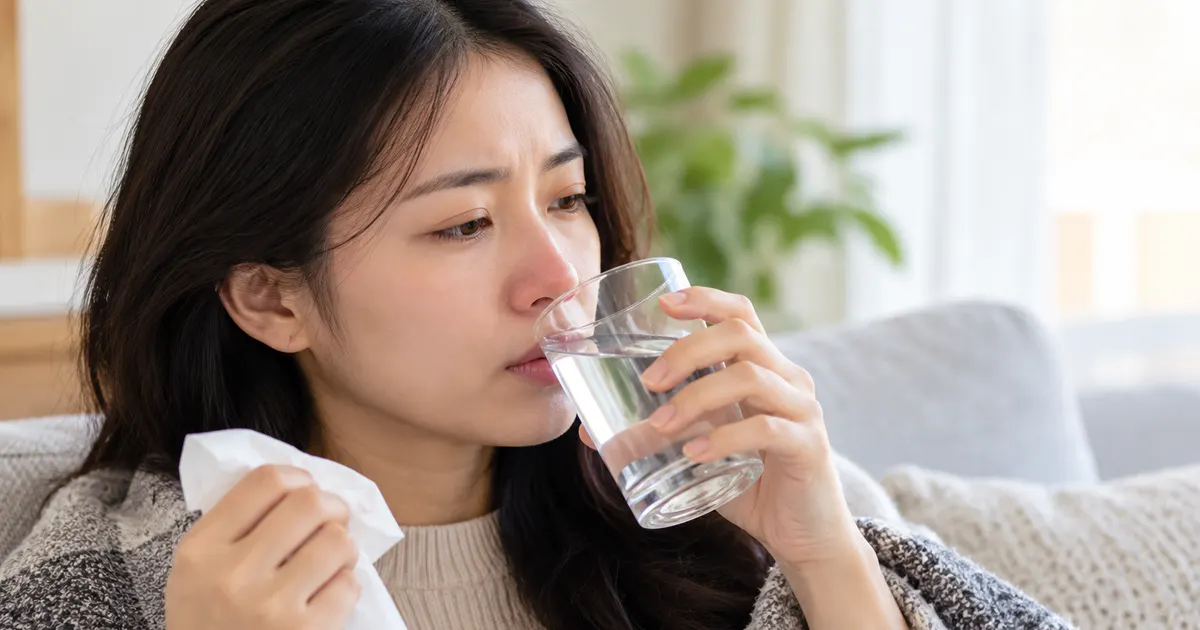 Người bệnh nghỉ ngơi và uống nước khi chăm sóc viêm mũi tại nhà
